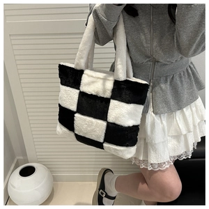 Detail of checkered plush tote bag on model showing soft lamb wool texture and large size
