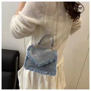 Detailed shot of retro denim blue tassel crossbody bag with golden metal chain strap