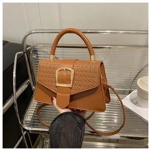 Détail du sac en cuir marron avec rabat tressé et boucle carrée dorée élégante
