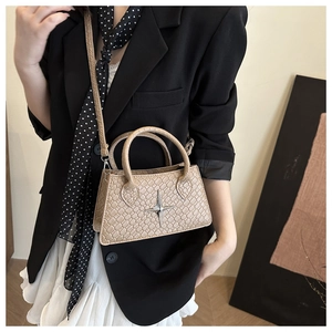 Detailed view of beige crocodile embossed tote bag featuring a silver star metal charm