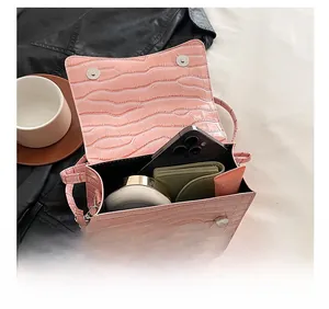 Internal capacity of pink croc-embossed small square bag holding phone and makeup