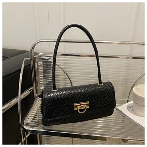 Detail of black crocodile texture faux leather on underarm bag with gold twist lock closure