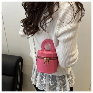 Detailansicht einer rosa Mini-Beuteltasche mit goldener Kette, getragen von einem Modell