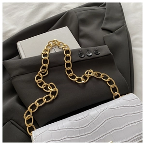 Gros plan du sac blanc à texture pierre avec chaîne dorée épaisse sur tissu gris