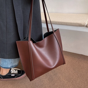 Detailed view of the dark brown tote bag showing smooth faux leather texture and strap