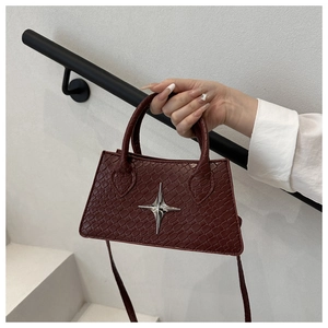Close-up of burgundy crocodile pattern square bag with silver star ornament detail