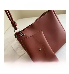 Detail view of caramel faux leather tote bag with matching envelope pouch and metal rivets