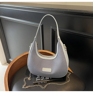 Close-up of light blue hobo bag with woven texture, metal logo and gold chain detail