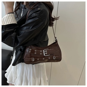 Detail of dark brown baguette bag with silver rivets and buckles on adjustable shoulder strap