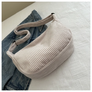 Detail of cream corduroy crescent bag showing fabric texture and adjustable strap