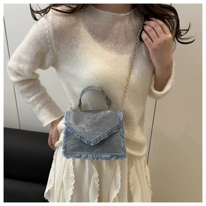 Detailed view of denim mini bag with dense fringe trim and elegant V-shaped flap cover
