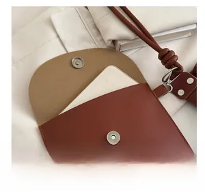 Close-up of a reddish-brown leather mini pouch accessory with a silver magnetic clasp