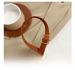 Close-up of adjustable brown leather shoulder strap with gold buckle and stitching