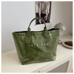 Detail of green tote bag featuring textured fabric and white printed lettering