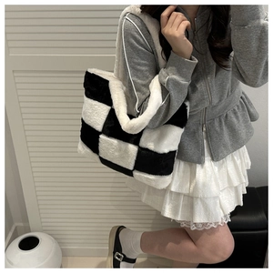 Detail view of plush black and white checkerboard tote bag with soft faux fur texture
