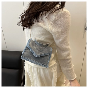 Detail of vintage denim blue mini bag with fringe trim and golden chain strap for women