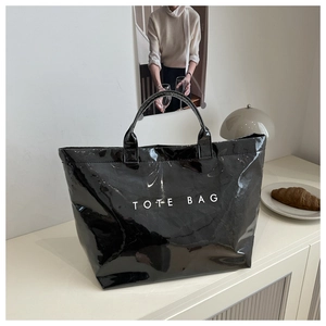Detail view of a glossy black tote bag with white text in an elegant French cafe setting