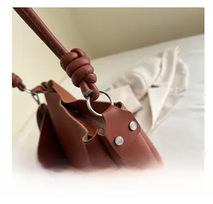 Detailed macro view of silver metal ring hardware and knotted strap on brown leather bag