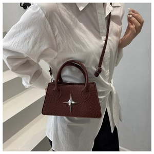 Detail of burgundy crocodile-textured crossbody bag with silver star-shaped metal buckle