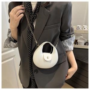Detail of off-white crescent bag with leather texture and gold chain worn with a gray blazer