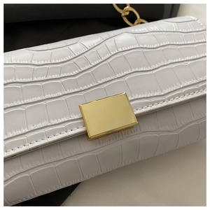 Gros plan du petit sac blanc gaufré croco avec boucle dorée et bandoulière chaîne