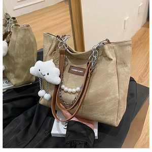 Detail of khaki canvas tote with pearl handle, chain strap and white plush cloud charm