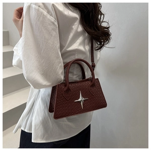 Cross-body view of a burgundy woven small square bag with star metal hardware on model