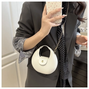 Detail of white crescent bag with gold snap button and chain strap shown on a model