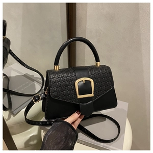 Détail d'un sac à main noir rétro avec texture tressée et grande boucle carrée dorée