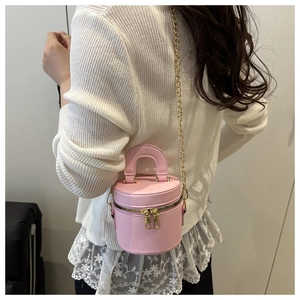 Nahaufnahme einer hellrosa Zylinder-Beuteltasche mit goldener Kette am Modell getragen
