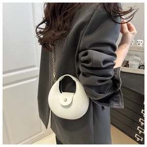 Sac demi-lune blanc chic avec chaîne dorée porté sur un blazer gris ajusté