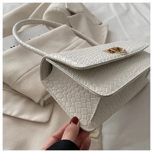 Detailed view of white faux snake leather handbag with gold buckle and circular handle
