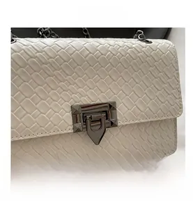 Macro detail of white woven leather texture with a dark gunmetal twist lock closure