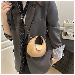 Detail of light brown crescent chain bag worn over the shoulder with retro minimalist style