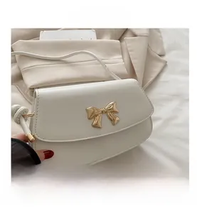 Gros plan du sac en cuir PU blanc avec boucle noeud en métal doré et fine bandoulière