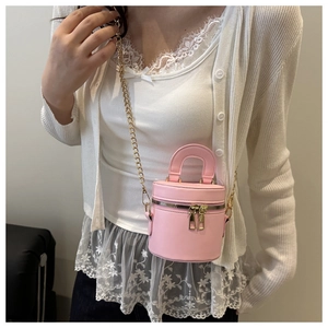 Nahaufnahme der rosa Mini-Eimertasche mit goldener Kette auf weißem Cardigan
