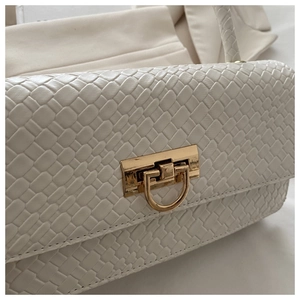 Close-up of white woven texture and elegant gold metallic arch clasp on the handbag