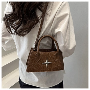 Detail of brown crocodile pattern mini handbag with silver star and cross-body strap