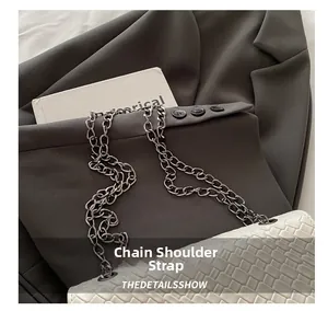 Detail of white woven texture shoulder bag featuring a dark grey metal chain strap