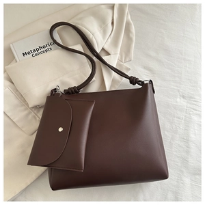 Close-up of chocolate brown leather tote bag with matching pouch on cream fabric