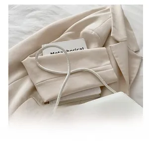 Gros plan d'un sac à bandoulière en cuir blanc avec un nœud décoratif en métal doré