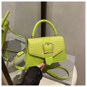 Détail du sac vert fluo avec texture crocodile et boucle dorée sur le rabat en similicuir