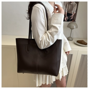 Detailed view of deep brown large tote bag featuring refined vertical stitching and slim straps