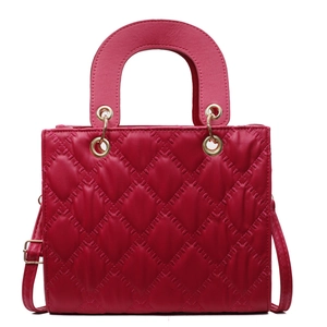 Classic red quilted handbag with gold hardware and top handle in a minimalist style
