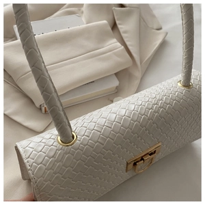 Detail of cream woven texture handbag with gold metal clasp and braided handle