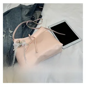 Pink faux leather shoulder bag featuring delicate lace ribbons and a pearl charm pendant