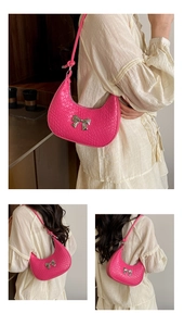 Detail of rose pink faux crocodile skin texture and silver bow buckle on crescent bag