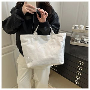 Detail of white textured tote bag with TOTE BAG embossed text and large capacity