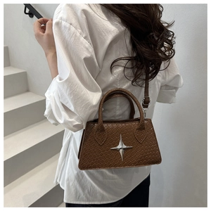 Detail of dark brown crocodile-embossed bag featuring silver star logo and double handles