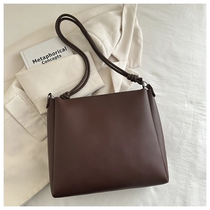 Detailed view of dark brown tote bag with knotted strap design and smooth texture